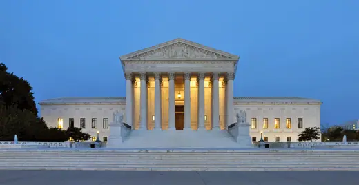 The west facade of the United States Supreme Court Building lit at dusk.