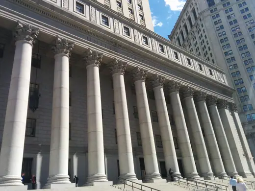 A granite federal courthouse with a columned portico and a gold-topped tower.