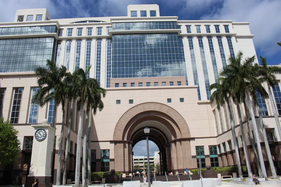 Tall modern courthouse of pale stone and glass with a colonnaded base, seen from the street.