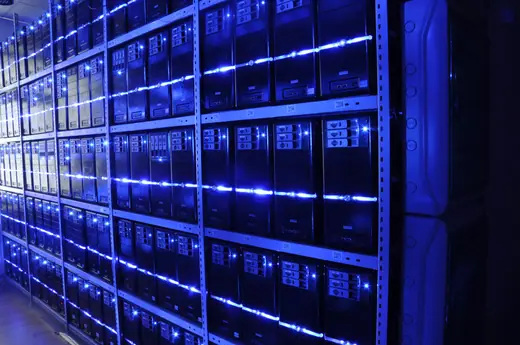 A row of server racks in a data centre, cables running along the aisle.